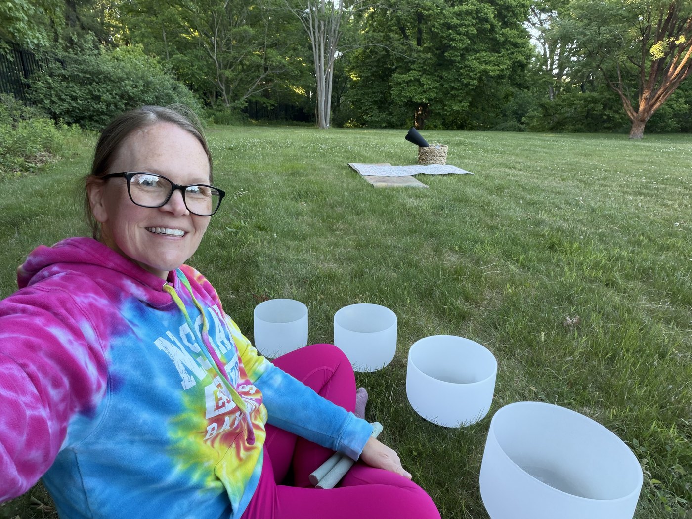 Lindsay seated outdoors with crystal singing bowls before a sound bath
